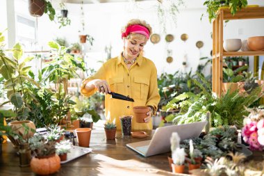 A woman in a yellow shirt is planting a succulent in a terracotta pot, enjoying the process
