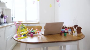 Paskalya yumurtası dekorasyonu için bir mutfak masası hazırlandı. Boyalar, fırçalar, renkli yumurtalar ve şenlikli dekorasyonlar.