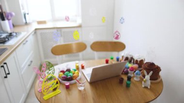 Paskalya için süslenmiş ahşap bir masa ile parlak bir mutfak sahnesi, boyalı yumurtalar, pastalar ve şenlikli süsler