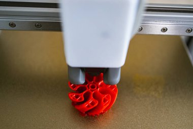 Bir 3D yazıcı nozülünün yakın plan görüntüsü erimiş plastiği katman katman kırmızı bir nesne oluşturmak için biriktiriyor