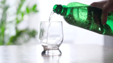Yeşil plastik şişeden cama dökülen köpüklü su. Yakın çekim.