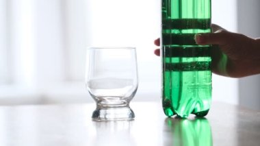 Yeşil plastik şişeden cama dökülen köpüklü su. Yakın çekim.