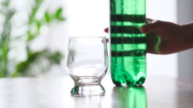Yeşil plastik şişeden cama dökülen köpüklü su. Yakın çekim.