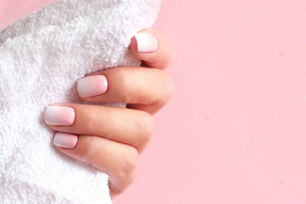 Gradient manicure and Hands Spa. Beautiful Woman hand closeup. Manicured nails and Soft hands skin. Beautiful woman's nails with beautiful baby boomer manicure, pink background. Copy space 
