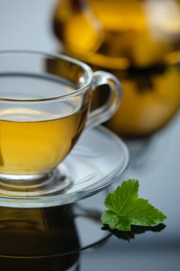 Cam bardakta yapraklı sarı bitki çayı. Yakın plan taze demlenmiş sıcak çay. Arka planda çaydanlık