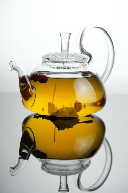 Cam çaydanlıkta sarı bitki çayı ve yapraklı böğürtlenli fincan. Yakın plan taze demlenmiş çay..