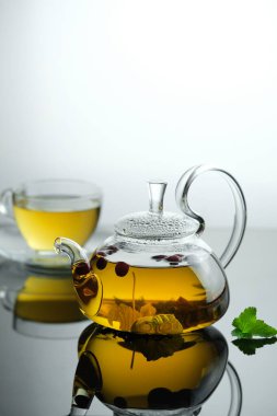 Cam çaydanlıkta sarı bitki çayı ve yapraklı böğürtlenli fincan. Yakın plan taze demlenmiş çay..