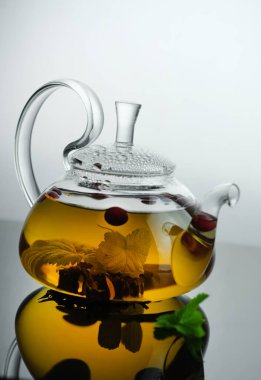 Cam çaydanlıkta sarı bitki çayı ve yapraklı böğürtlenli fincan. Yakın plan taze demlenmiş çay..