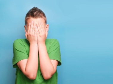 Duygusal açıdan sevimli çocuğun gerçek duygularını gösteren bir stüdyo çekimi. Mavi arkaplanda portre 