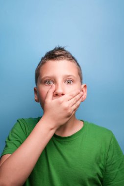 Duygusal açıdan sevimli çocuğun gerçek duygularını gösteren bir stüdyo çekimi. Mavi arkaplanda portre 
