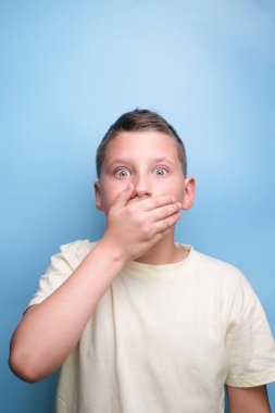 Çocuk elleri ile ağzını kapatıyor düşünceli, şüpheci ve masum, gerçek duygularını gösteriyor..