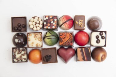 Bir sürü çikolatalı pralin, beyaz arka planda izole edilmiş çeşitli çikolatalı pralinlerin üst görüntüsü.,