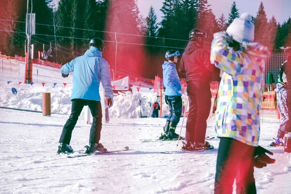 Estación de esquí, una chica mira a la montaña de esquí en la que los esquiadores están bajando —  Fotos de Stock