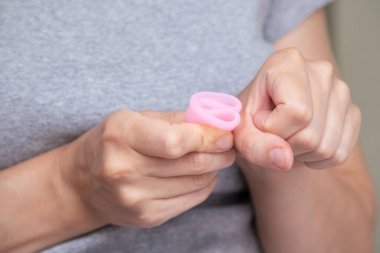 Kadınların el katlama regl bardağını kapatarak nasıl kullanılacağını göster. Kadın sağlığı konsepti, sıfır atık alternatif,