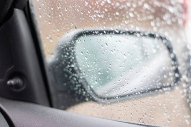Arabanın cam zemininde bulanık yağmur damlası, araba vitrininde su damlası.