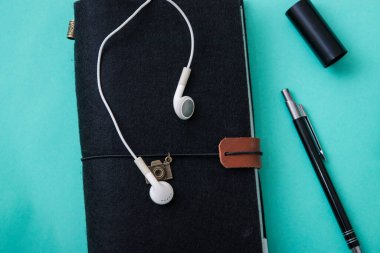 Turkuaz bir masa üzerinde eflatun bir defter ile düz uzanan blogger veya serbest çalışma alanı,