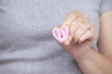 Kadınların el katlama regl bardağını kapatarak nasıl kullanılacağını göster. Kadın sağlığı konsepti, sıfır atık alternatif,