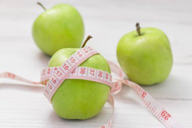Beyaz arka planda yeşil elmaya sarılı şerit ölçme, kilo verme hedefi kavramı, beslenme amacı,