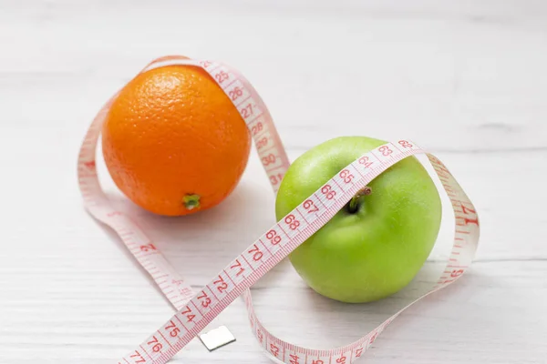 Nastro di misura avvolto intorno a due mela verde e arancio isolato su sfondo bianco, Concetto dell'obiettivo di perdere peso, l'obiettivo della dieta, — Foto Stock