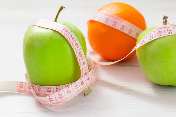 Nastro di misura avvolto intorno a due mela verde e arancio isolato su sfondo bianco, Concetto dell'obiettivo di perdere peso, l'obiettivo della dieta, — Foto Stock