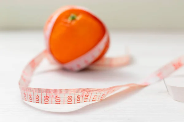 Nastro di misura avvolto intorno arancione su sfondo bianco, Concetto dell'obiettivo di perdere peso, l'obiettivo della dieta, — Foto Stock