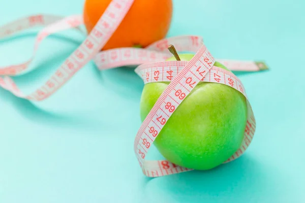 Nastro di misura avvolto intorno a due mela verde e arancio isolato su sfondo bianco, Concetto dell'obiettivo di perdere peso, l'obiettivo della dieta — Foto Stock