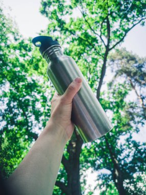 Sıfır atık. Sıfır atık, yeşil ve bilinçli yaşam tarzı konsepti. İçki konteynırı fikrinde yeniden kullanılabilir. Demir şişe doğa arka planında