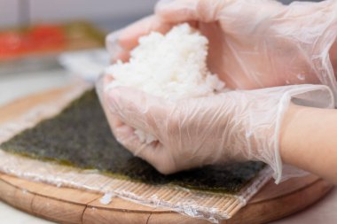 Aşçının elleri yakın plan. Bir şef suşi yapar ve pirinçten, kırmızı balıktan, avokadodan ve Philadelphia peynirinden rulo yapar. Adım adım. Adım 2