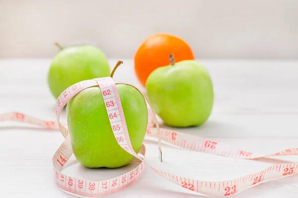 白い背景に2つの緑のリンゴとオレンジの周りに包まれたテープを測定 減量する目標の概念 食事の目標 — ストック写真