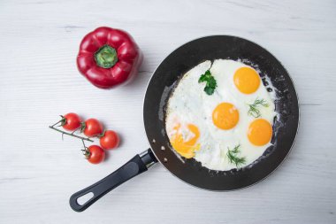 Tava biberli omlet, açık ahşap bir masanın arka planında vişneli domates. Ulusal Ukrayna ya da Beyaz Rusya yemekleri. Kahvaltı, öğle yemeği. Üst görünüm, seçici odak, kırsal biçim