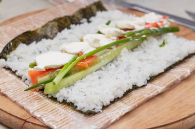 Cook's hands close-up. A chef makes sushi and rolls from rice, red fish, avocado and philadelphia cheese. step by step