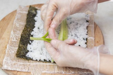 step 2. Cook's hands close-up. A chef makes sushi and rolls from rice, red fish, avocado and philadelphia cheese. step by step