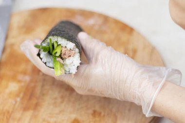step 3. Cook's hands close-up. A chef makes sushi and rolls from rice, red fish, avocado and philadelphia cheese. step by step