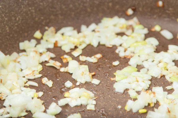 Close up view of the fried onion on a frying pan. Selected Focus.