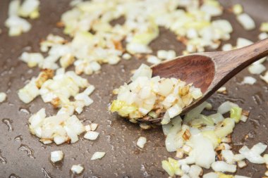 Close up view of the fried onion on a frying pan. Selected Focus.