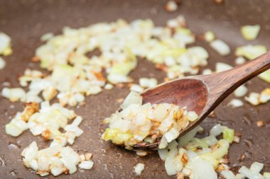 Close up view of the fried onion on a frying pan. Selected Focus.