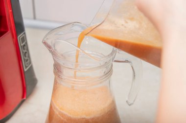 Woman making fresh drink. Juice and apple juice. Fruits in background. Clean eating, detox concept
