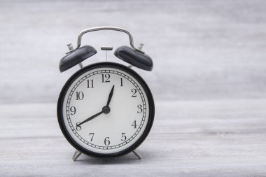 black vintage alarm clock standing on the table with color background shows 12 hours 40 minutes in evening or morning. Time to choice concept,