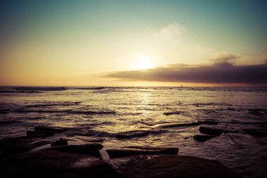 Kaliforniya kıyısındaki kayalık bir sahilden gün batımı.