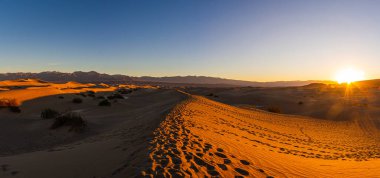 Ölüm Vadisi 'ndeki kum tepelerinden oluşan bir panorama. Ölüm Vadisi Ulusal Parkı' nda güneş doğarken soba kuyuları yakınında..