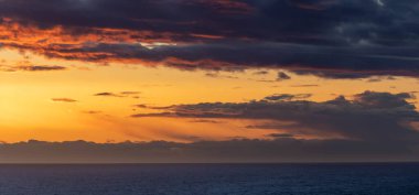 Gökyüzünde canlı renkler ve kara bulutlarla akşam bulutları manzarası.