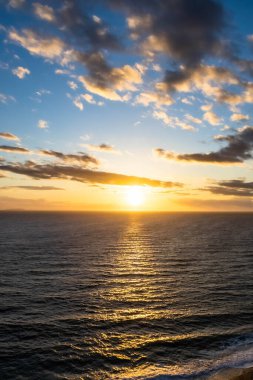 Okyanus üzerinde dramatik bir gün batımı. Renkli gökyüzü ve renkler aşağıdaki dalgalara yansıyor..