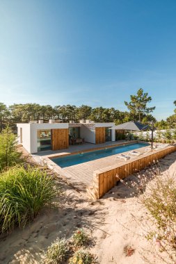 Bahçe havuzu ve ahşap güvertesi olan modern bir ev.