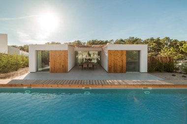 Bahçe havuzu ve ahşap güvertesi olan modern bir ev.