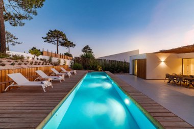 Bahçe havuzu ve ahşap güvertesi olan modern bir ev.