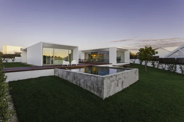 Bahçe havuzu ve ahşap güvertesi olan modern bir ev.