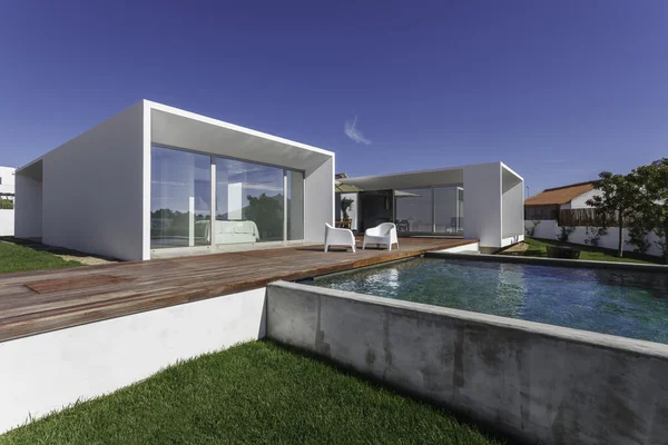 Bahçe havuzu ve ahşap güvertesi olan modern bir ev.