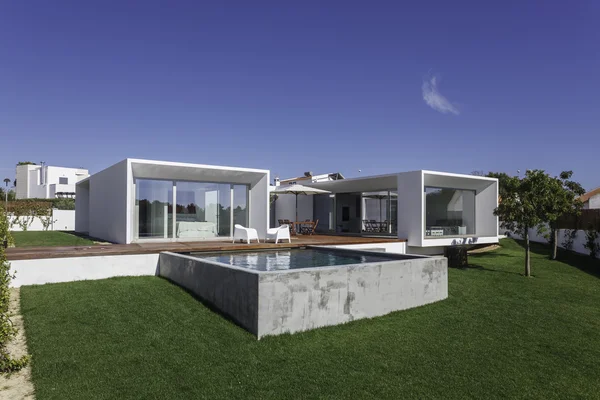 Bahçe havuzu ve ahşap güvertesi olan modern bir ev.