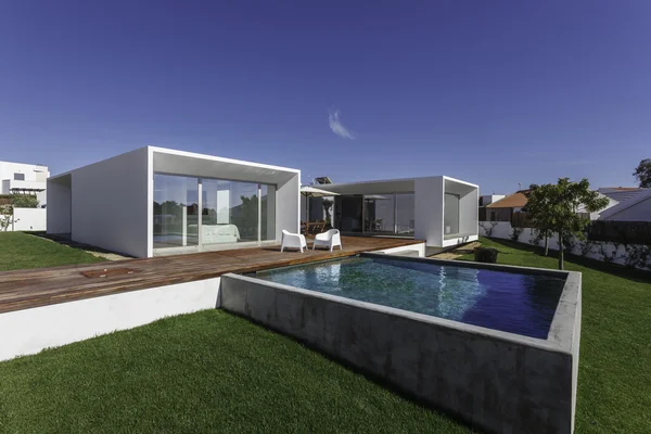 Bahçe havuzu ve ahşap güvertesi olan modern bir ev.