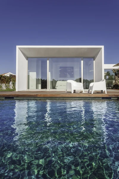 Bahçe havuzu ve ahşap güvertesi olan modern bir ev.